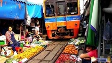 泰国火车经过菜市场，里面的人还慢悠悠的，根本不把火车当回事