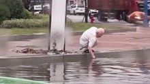 暴雨过后路口积水严重，白发老人穿一身整洁白衣，弯腰赤手清理下水道杂物！